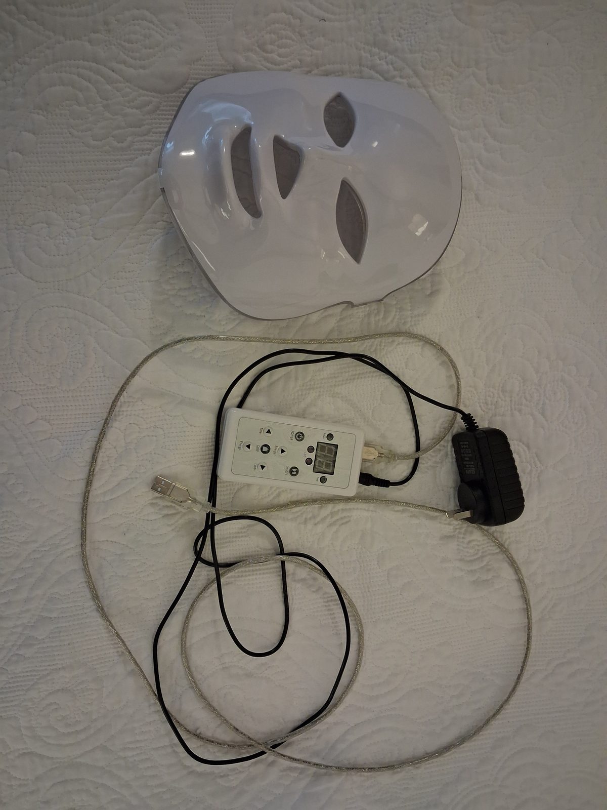 Older unidentified rigid white LED face mask with cables and an external controller